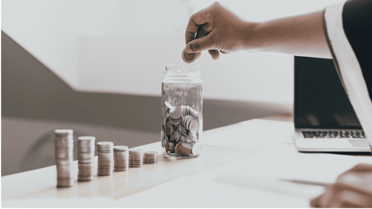 Persona con el poder del hábito del ahorro depositando monedas en un tarro de vidrio