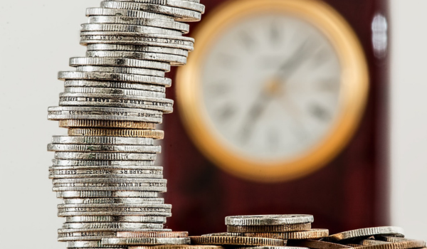 Torre de monedas frente a reloj simbolizando el crecimiento de patrimonio